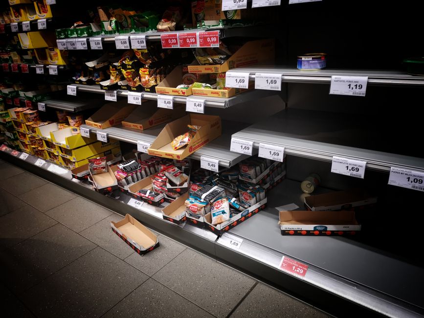Image of supermarket shelves displaying various snack and confectionery items, including chocolate bars and candies, in open and closed boxes. The items are arranged in rows with price tags visible be